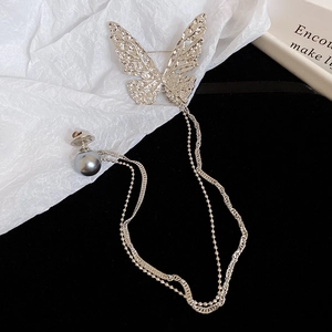 Detailed view of silver butterfly brooch with hammered texture and pearl chain fringe