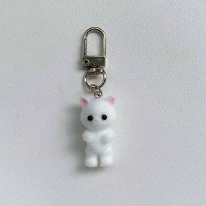Macro detail of the white flocked cat keychain with soft fuzzy texture and silver clip