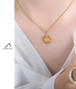 Close-up of a golden stainless steel sun pendant necklace worn on the collarbone