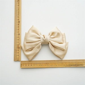 Close-up of a large three-layer champagne satin bow hair clip measuring 15cm in width