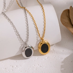 Elegant gold and silver necklaces with black oval pendants shown on minimalist props