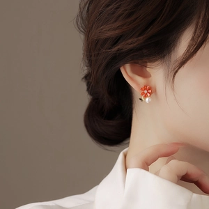 Gros plan de boucles d'oreilles fleurs orange en zircon et perle sur un mannequin