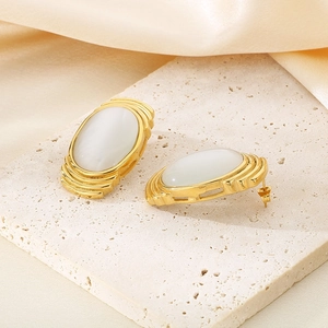 Macro detail of French vintage earrings with gold texture and white oval opal stone