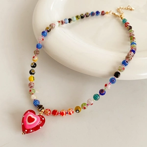 Close-up of millefiori glass bead necklace with a pink heart pendant and gold clasp