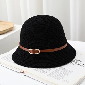 Detail of black knit bucket hat with brown leather strap and gold buckle on a magazine