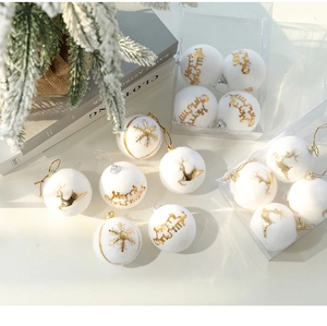 Detailed view of white flocked Christmas ball with gold reindeer and snowflake patterns