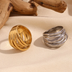 Detail view of gold and silver multi-layer twisted rings on a natural wood surface