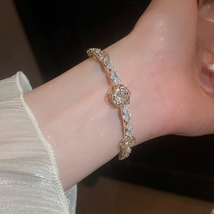 Detail of 14k gold plated bangle featuring a crystal flower and marquise zirconia