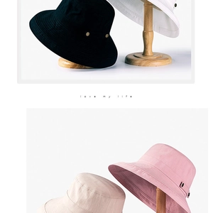 Détail de chapeaux de soleil en coton noir et blanc sur supports de tête en bois