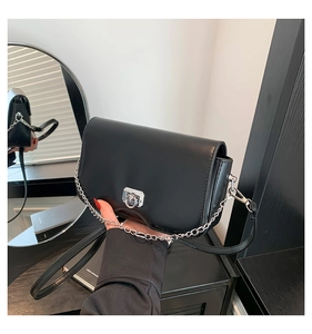 Détail du sac bandoulière en cuir noir avec fermoir anneau argenté et design courbe en bas