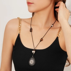 Gros plan du collier ethnique avec pendentif ovale en bois et détails argentés fins