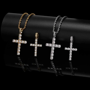 Macro view of four iced out cross pendants in gold and silver with twist chains