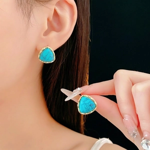 Vintage gold-plated triangle turquoise earrings with natural stone texture on black background
