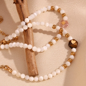 Detail of beaded bracelet with white shell pearls, gold spacers and heart charms