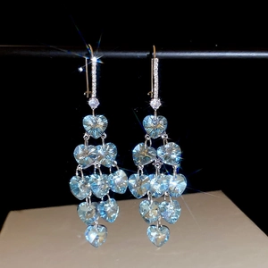 Macro detail of luxury light blue heart-shaped crystal earrings with tassel drops