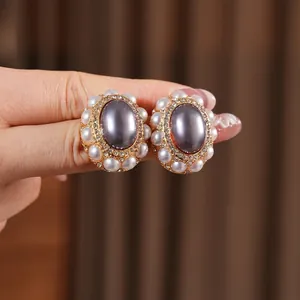 Vintage zircon earrings with purple stone and pearl halo held for scale