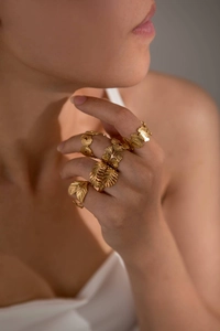 Close-up of stacked gold titanium steel rings with intricate vintage leaf textures