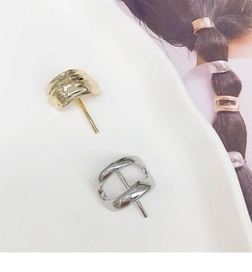 Detail view of gold and silver minimalist metal ponytail hooks on a ceramic plate