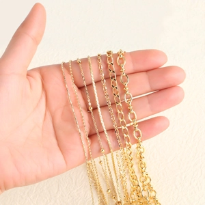Selection of gold plated jewelry chains including ball and link styles held by hand