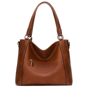 Detail of brown PU leather tote bag showing soft texture and functional front zipper pocket