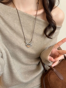 Detail of vintage wooden horse pendant on brown leather cord worn with beige knit sweater