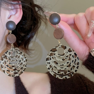 Detail of layered resin hoop earrings with leopard print and matte dark brown circular studs