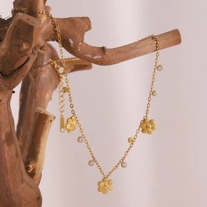 Close-up of 18K gold plated necklace with zircon flower pendant on a natural branch