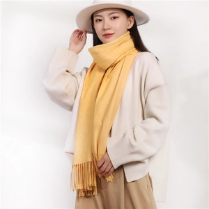 Elegant mustard yellow cashmere-feel scarf with fringes styled on a female model
