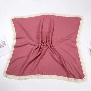 Dettaglio della coperta in mussola rosa con trama increspata e frange con nappe