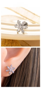 Detailed snowflake stud earrings with cubic zirconia shown in real-life ear piercing wear