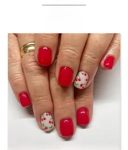 Short square press-on nails with red glossy finish and cherry pattern on a white base