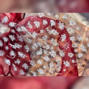 Vue macro de stickers nail art 3D gaufrés avec fleurs blanches et détails strassés