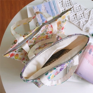 Détail de sacs en coton à imprimé floral et fruits avec fermeture éclair sur table