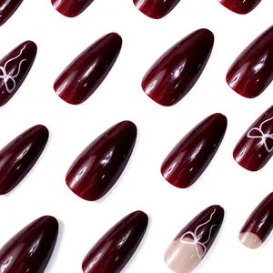 Glossy burgundy almond press-on nails set featuring white bow-knot patterns