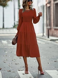 Détail d'une robe rouge brique à manches longues avec volants étagés et taille froncée