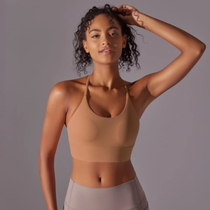 Detail of light brown halter yoga bra with thin straps and wide elastic hem on model