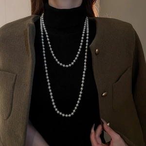 Detailed close-up of double-layer dark grey faux pearl necklace on elegant model