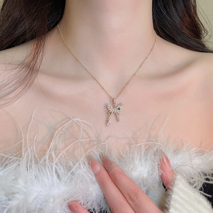 Close-up of elegant gold butterfly necklace with green and clear zircon stones on neck