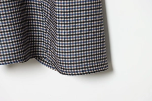 Detail of blue and brown houndstooth fabric midi skirt showing high-quality twill texture