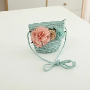 Detailed close-up of a mint green woven straw bag with colorful floral 3D decorations