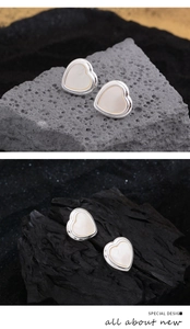 Detailed view of silver heart earrings with white shell inlay on natural rock backgrounds