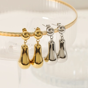 Polished 18K gold and silver water drop earrings displayed on glass crystal edge