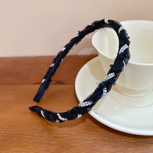 Detail of elegant black mesh headband with sparkling rhinestone accents on a white cup
