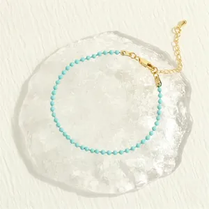 Detail of light blue beaded bracelet with gold lobster clasp and extension chain