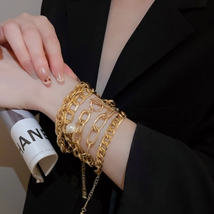 Detailed macro of gold layered chain bracelets with pearl and toggle clasp closure