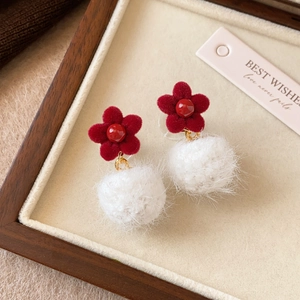 Detailed close-up of red flocked flower earrings with soft white pompom pendants