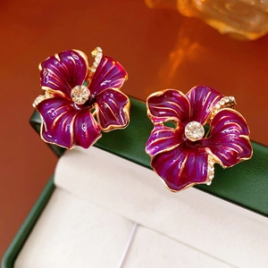 Macro view of vintage enamel flower earrings with purple petals and sparkling crystals