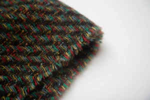 Detailed macro view showing multi-color herringbone weave texture of the wool scarf