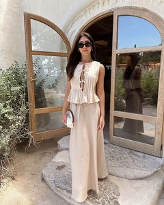 Detail of beige linen two-piece set featuring sleeveless tie-up top and high-waisted skirt