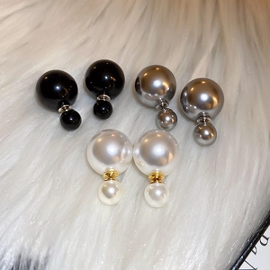Macro view of double-sided pearl earrings in black, silver, and white on plush background